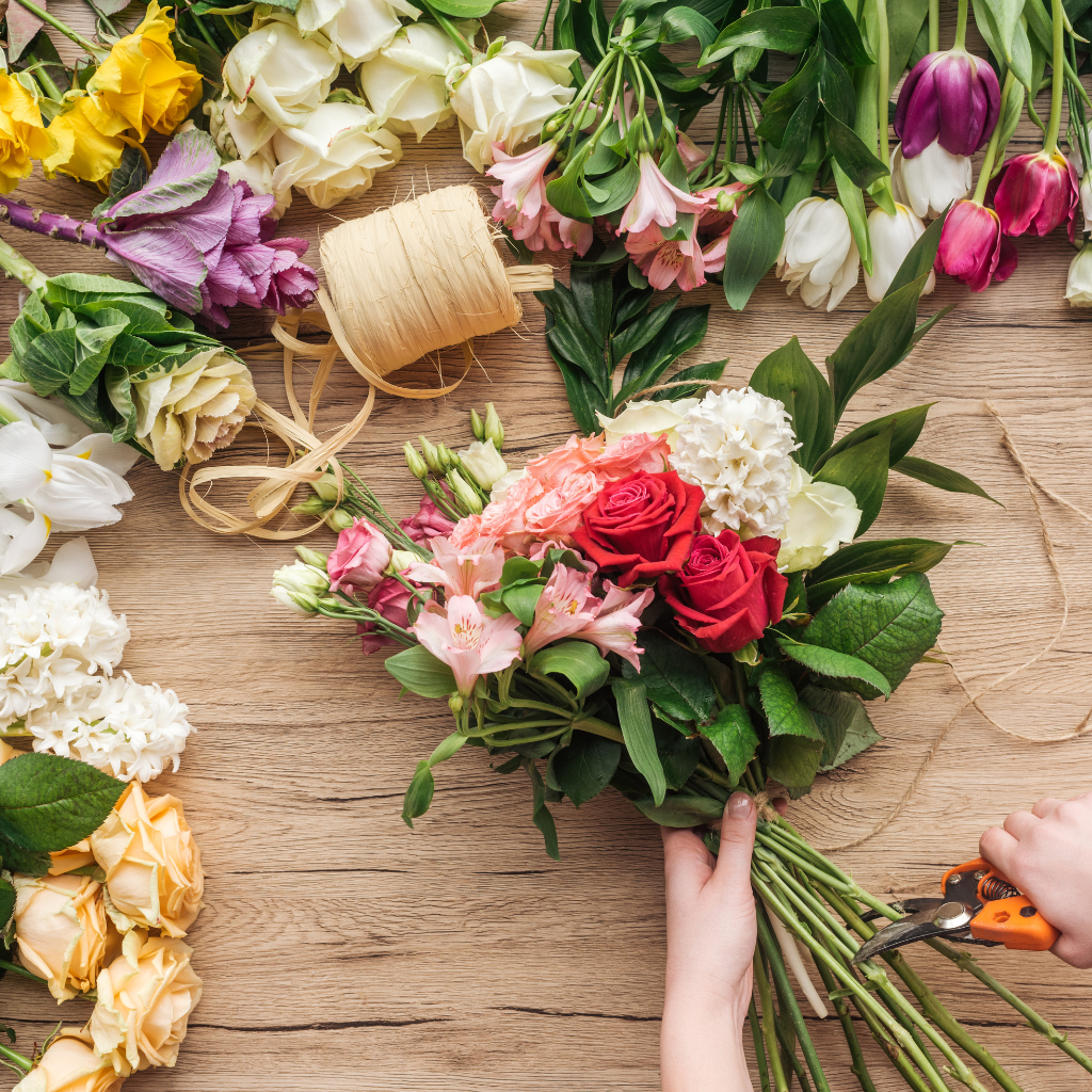 Hands arranging a bouquet with various flowers