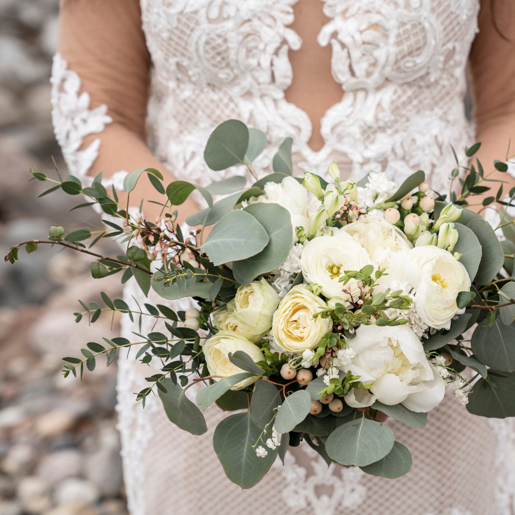 A bride gracefully holds her bouquet while standing on the rocks.