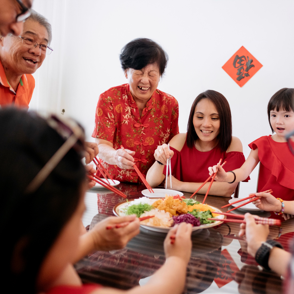 a singaporean family doing lohei to celebrate chinese new year