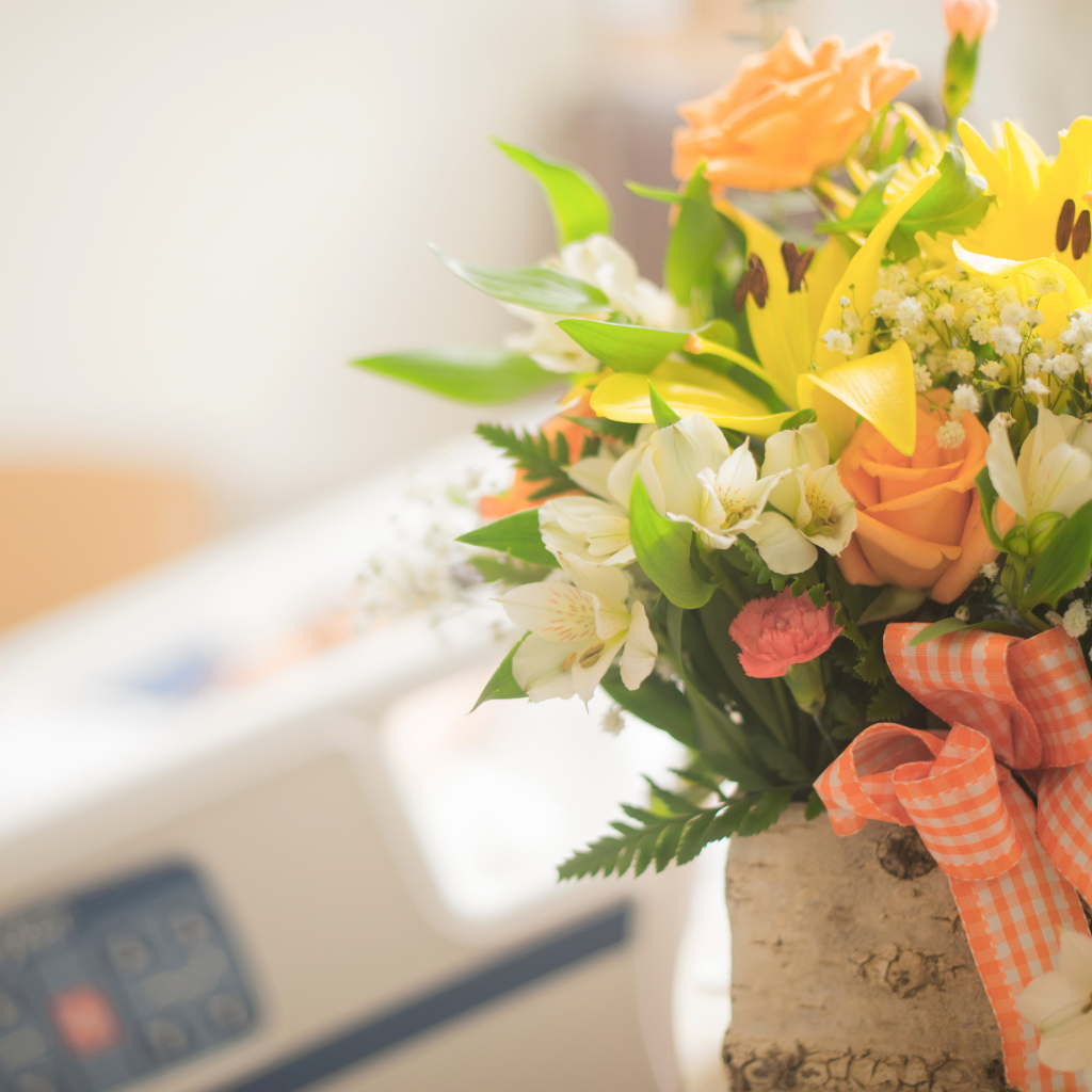 Bouquet of vibrant get-well soon basket flowers beside a hospital bed