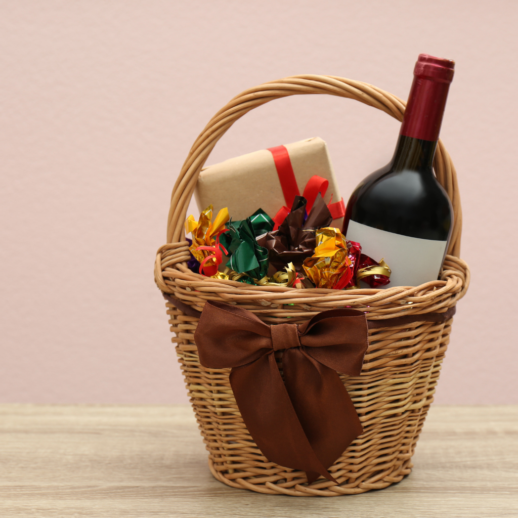 Gift basket hamper with wine, treats, and a present, adorned with a brown bow