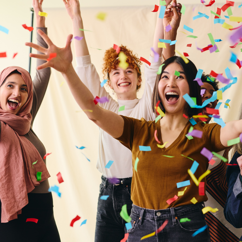 A joyful group of young women celebrating a special occasion, throwing colorful confetti in the air.