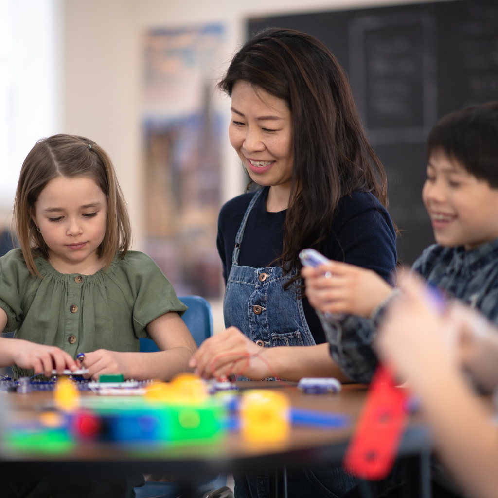 A group of students collaborating with their teacher on a project, engaged in a productive and interactive learning environment.