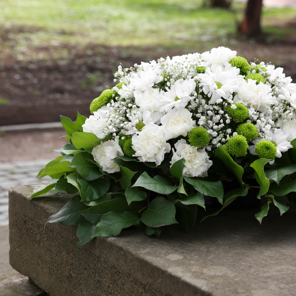 A floral arrangement of white flowers and greenery typically used for funerals.