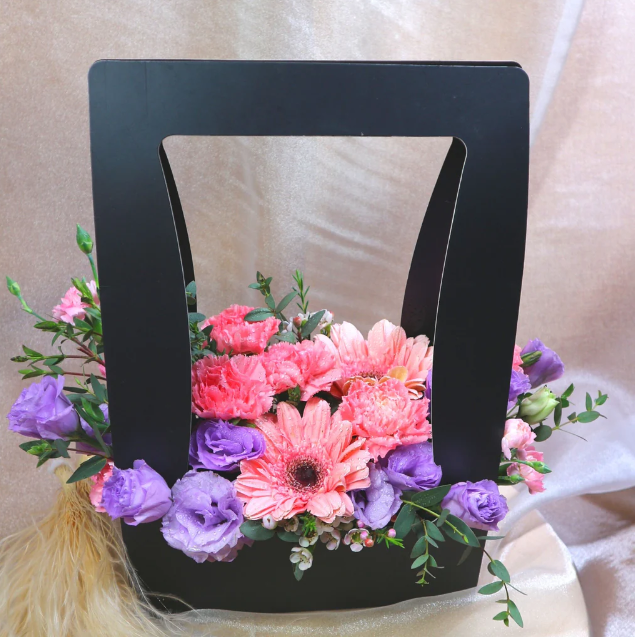 florabasket-pink-gerberas-purple-eustomas-and-pink-carnations-black-basket-complemented-by-neutral-colored-backdrop