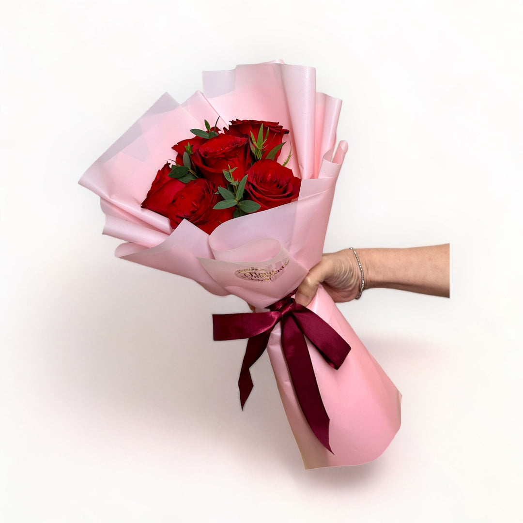 bouquet-of-6-stalks-red-roses-wrapped-in-pink-hand