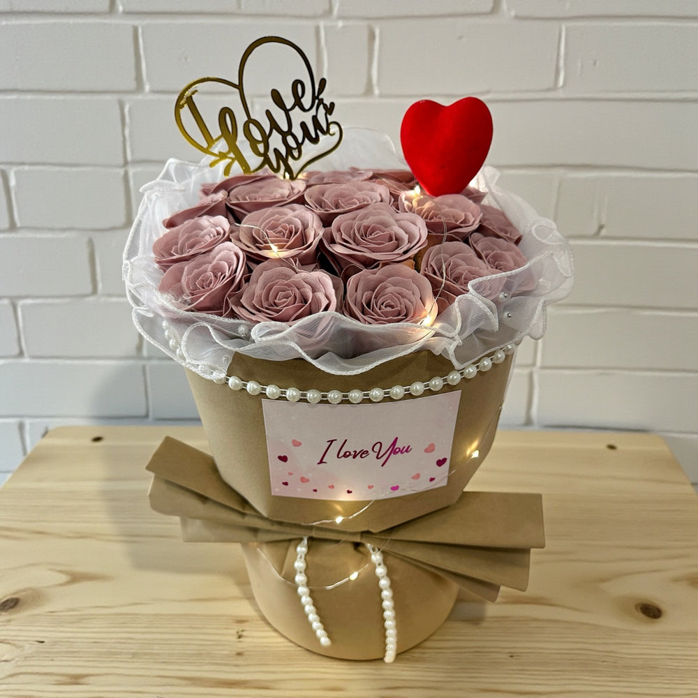 Bouquet of cappuccino roses in a decorative container with 'I Love You' sign on a wooden surface.