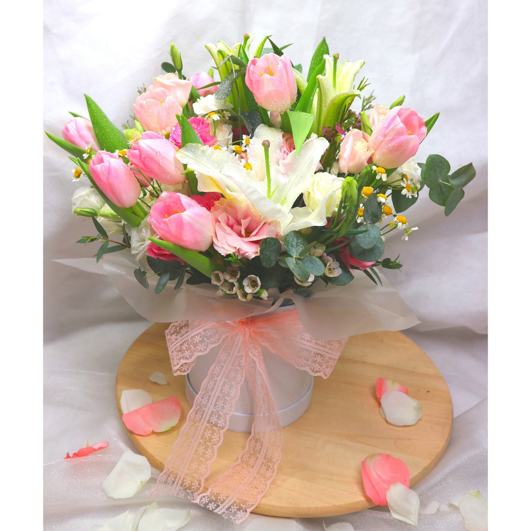 flowerbox-lilies-tulips-eustomas-eucalyptus-leaf-with-set-on-a-wooden-plate-with-a-backdrop-of-white-cloth